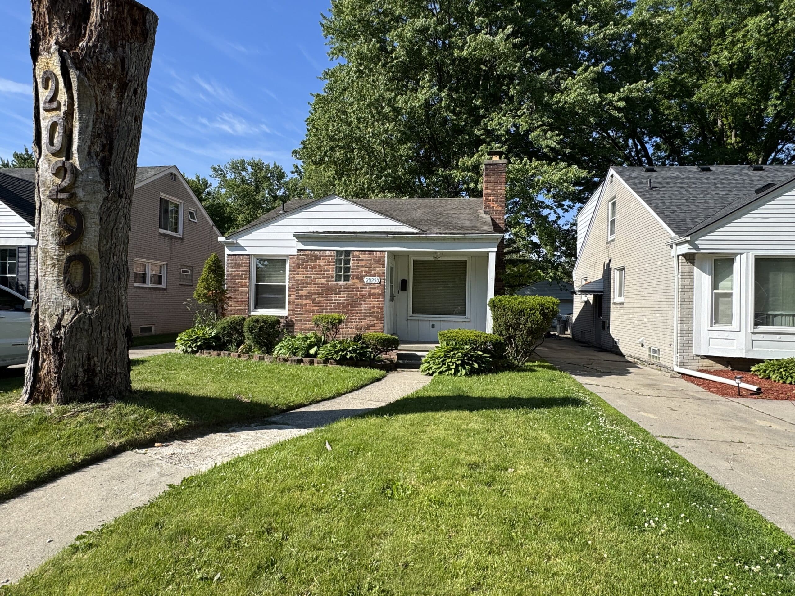 Brick ranch house with a large cut tree trunk in the front yard in Holt